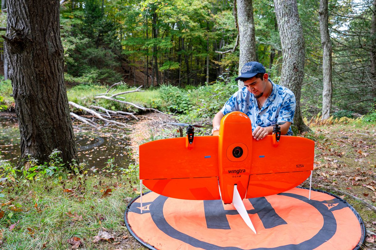 researcher preparing a drone to study the beaver damn in the backgound