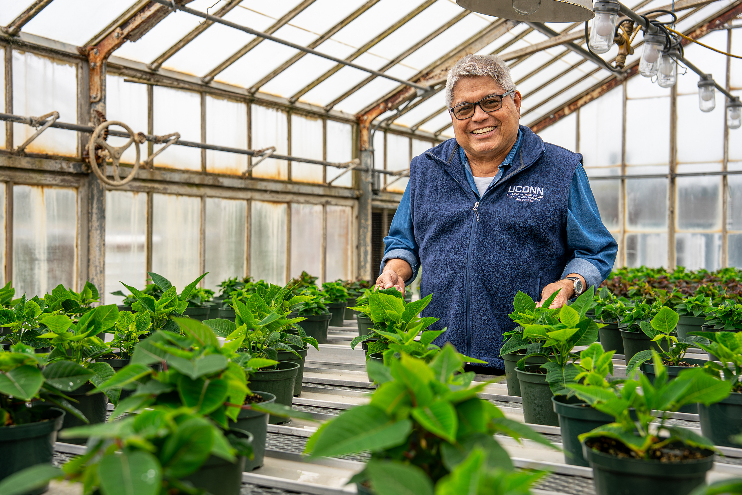 Rigoberto Lopez showing off plant in a greenhouse